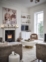 Neutral living room with fireplace, coffee table and shelves featuring vases and ornaments