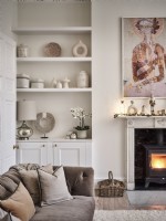 Neutral living room with seating, fireplace, artwork and shelves featuring vases