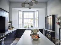 Classic kitchen featuring black units, white Island unit and decorative plants