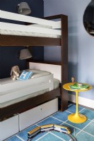 Boys blue bedroom with bunk beds and colourful square patterned rug.