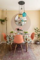 Orange chairs around small dining table with retro tablecloth