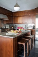 Modern kitchen with marble top island and many wooden storage cupboards.