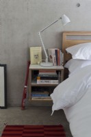 Contemporary bedroom, bedside table and concrete flooring and walls