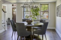 Modern dining room with round wooden dining table and upholstered chairs.