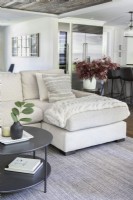 Modern white sectional sofa with cushions and throw blanket.
