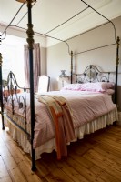 A four poster bed on stripped varnished wooden floors.