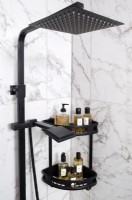 Detail of black shower head and shelving on marble tiled wall