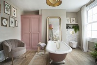 Vintage style feminine bathroom with pink rolltop bath and wardrobe