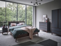 Bed in front of glass wall in modern bedroom