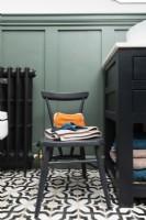 Detail of small bathroom chair on monochrome patterned tile floor