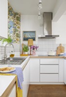 Open-plan kitchen with botanical wallpaper and white tiles.
