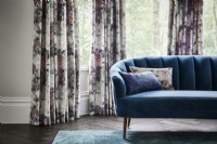 Sofa and cushions in front of patterned curtains