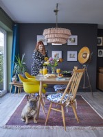 Open plan dining area with yellow vintage style chairs, a patterned rug and dark blue painted walls.