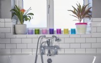 Bathroom detail with white metro tiles and colourful candles on the window shelf.