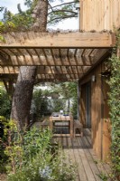 Wooden dining table on decking under pergola