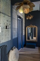Dark blue painted hallway with gold accessories 