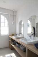 Arched mirrors over twin sinks with arched window