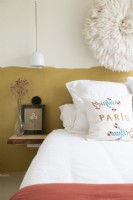 Embroidered pillow on bed with half painted wall behind