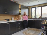 Kitchen with dark brown cabinets, gold wallpaper and mirror tiles.