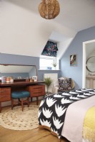Bedroom with an ensuite bathroom, blue painted walls and mid-century furniture. 
