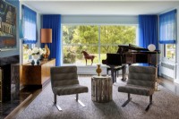 Music room with piano and two houndstooth patterned chairs.