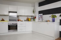 Contemporary kitchen in an open plan living space. With white cabinets and black and white striped walls.