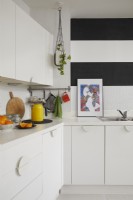 Contemporary kitchen in an open plan living space. With white cabinets and black and white striped walls.