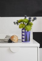 Kitchen detail showing a purple concrete vase, hexagon tiles and black and white striped painted walls.
