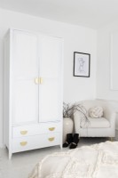 Corner of a white bedroom with freestanding wardrobe and chair 