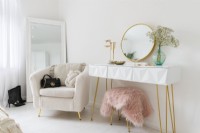 Corner of a white bedroom with chair and dressing table