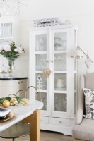 Tall reclaimed white hand painted cabinet with glass panelled doors in an open plan kitchen diner