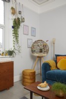 Living room detail with a birdcage, teal blue sofa, orange and yellow cushions and a retro coffee table.