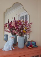 Living room detail showing upcycled cabinet with a vase of dried flowers and a dog ornament.