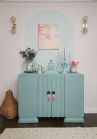 Living room showing upcycled turquoise cupboard with painted wall detail and an abstract painting.