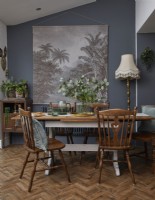 Dining area with vintage wooden furniture, dark grey walls and botanical artwork.