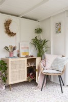 Corner of a dried flower craft room with rattan chair and storage cupboard