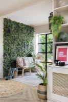 Cane sofa in front of an artificial plant wall