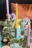 Pastel coloured candles and foliage decorations on dining table