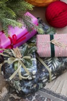 Detail of colourfully wrapped Christmas gifts under tree