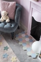 Detail of pastel hexagon tiled hearth next to pink fireplace