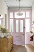 Pink painted front door and chandelier in vintage style hallway