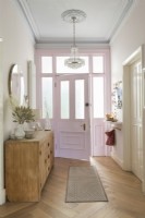Pink painted open front door in classic style hallway