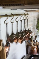 Detail of copper pans hanging on butchers hooks above cooker
