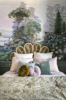 Colourful mural behind bed with wicker headboard