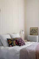 Simple country bedroom with colourful cushions on bed