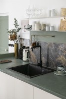 Detail of sink with marble splashback and grey concrete worktop