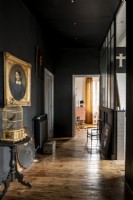 Gilded picture frame and decorative birdcage in black painted hallway