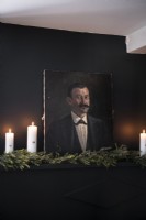 Detail of classic portrait against black wall with candles and garland