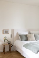 Simple white bedroom with pale grey cushions and bedspread