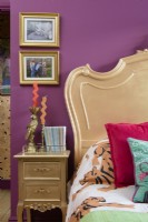 Gold painted French bed and side table in a pink bedroom
